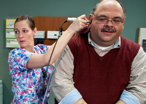 Veteran receiving ear test from primary care provider.